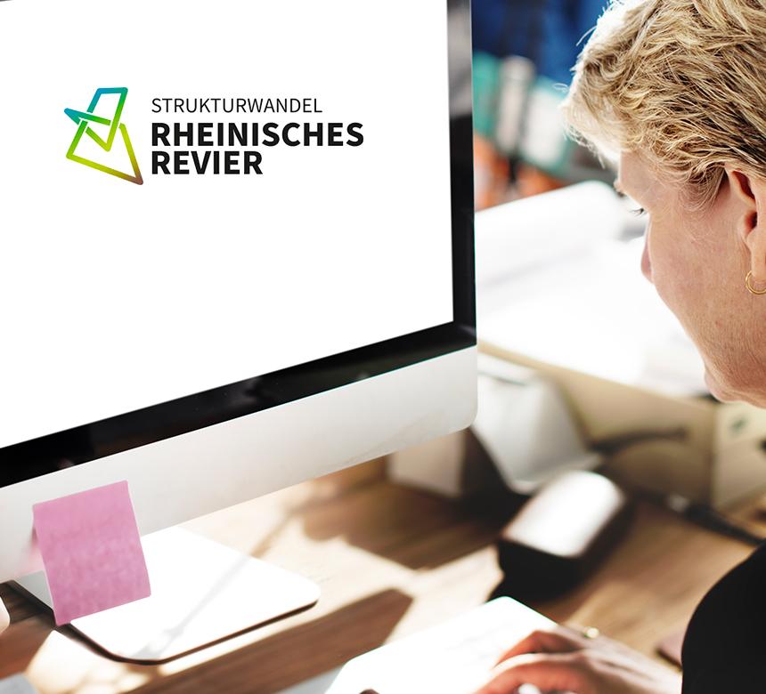 Eine Person arbeitet an einem Computer, auf dem Bildschirm ist das Logo der Zukunftsagentur Rheinisches Revier zu sehen.