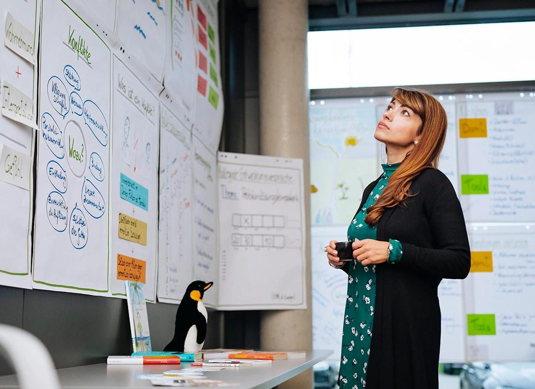 Frau steht vor einer Wand voll mit beschriebenen Flipchart-Bögen