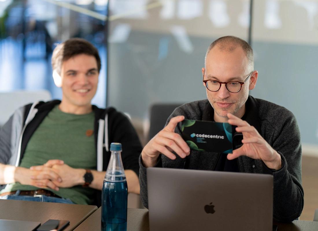 Zwei Mitarbeiter sitzen hinter einem Laptop